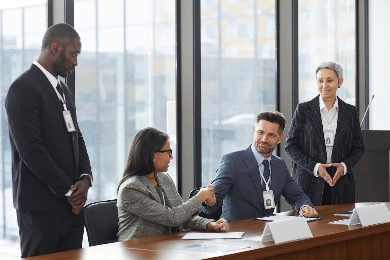 Profesionales estrechando manos sobre una mesa de conferencias durante una reunión formal en la oficina.